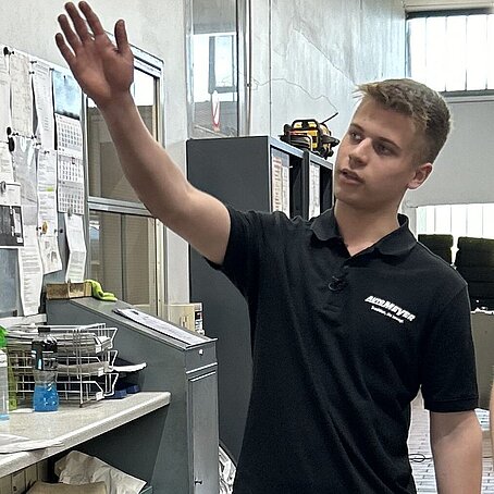 Paul Azubi im Autohaus Meyer zeigt auf die Aufträge 