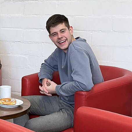 Industriekaufmann Niklas sitzt in einem roten Sessel