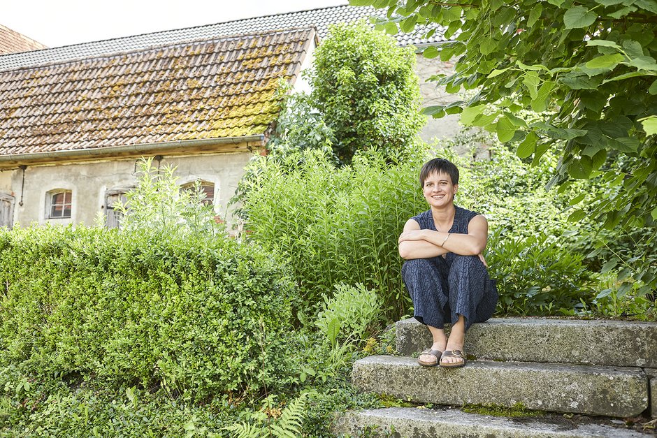 Theresa May sitzt auf Treppe im Grünen