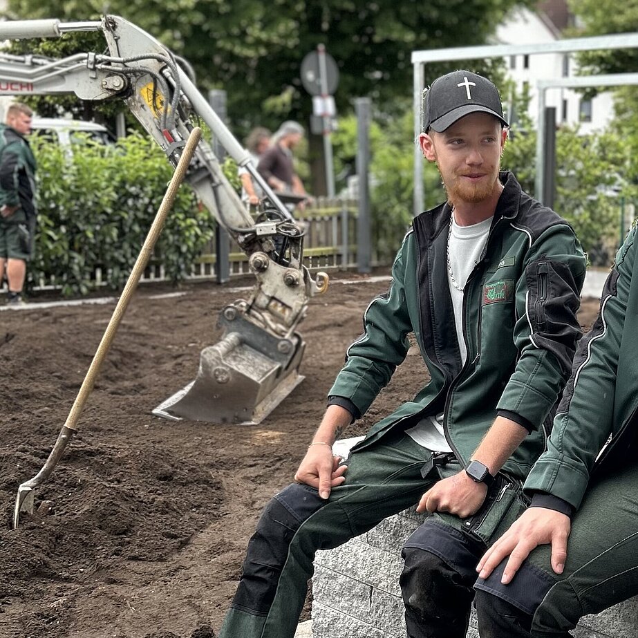 Hristoph und Jobchecker Julian sitzen in einem Garten, Bagger